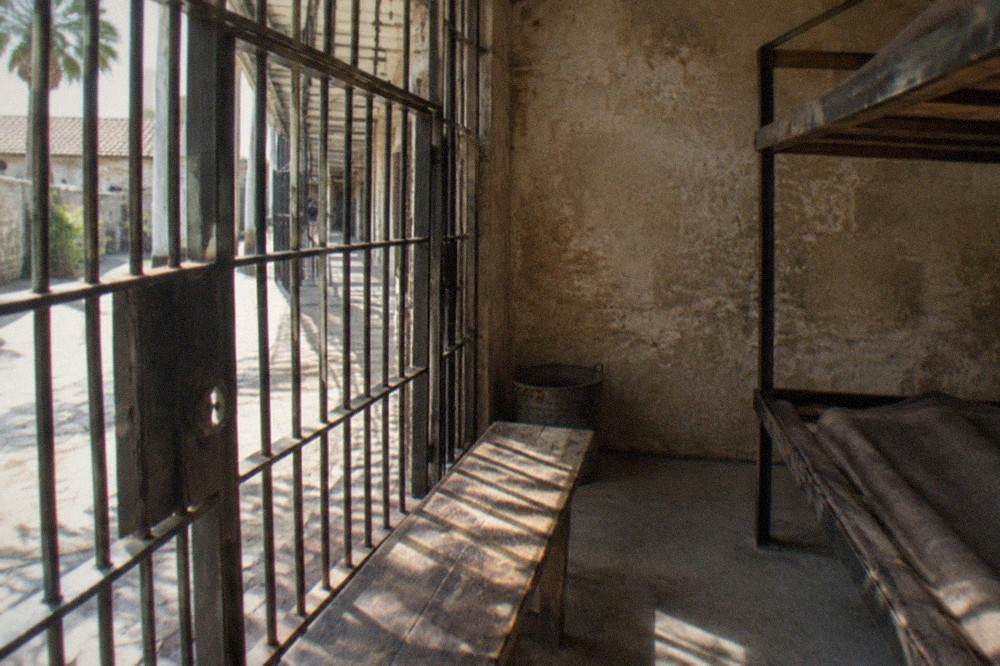 Old Jail cell block interior with iron bars and a wooden bench