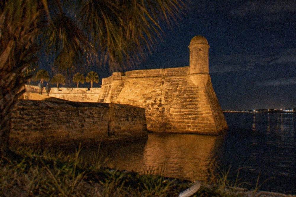 A stone coquina wall of the old fort lit warmly at night