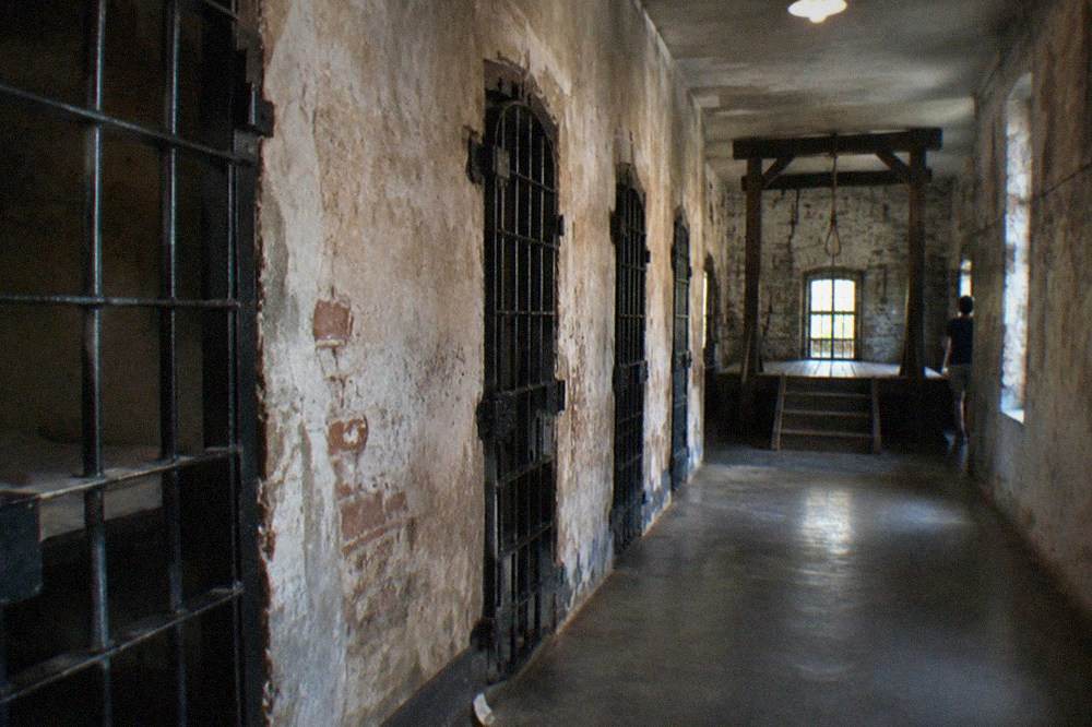 A dimly lit corridor inside the Old Jail with a wooden gallows structure at the end