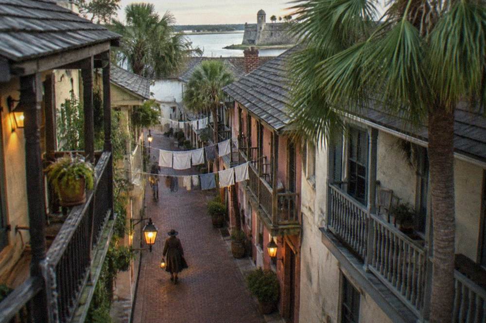 Lantern-lit narrow historic street with old balconied buildings at dusk in St. Augustine