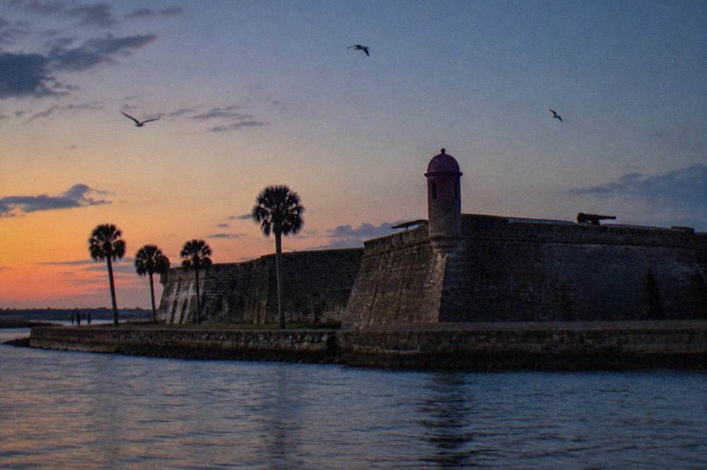 An old stone fort wall rising against a dark evening sky