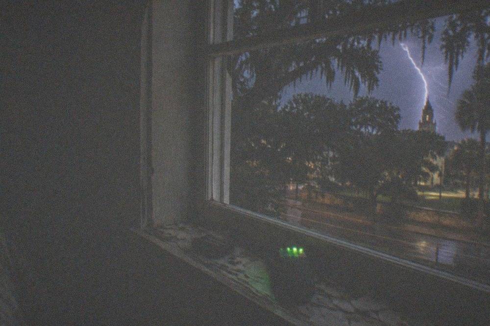 A handheld EMF meter glowing in a dark historic interior