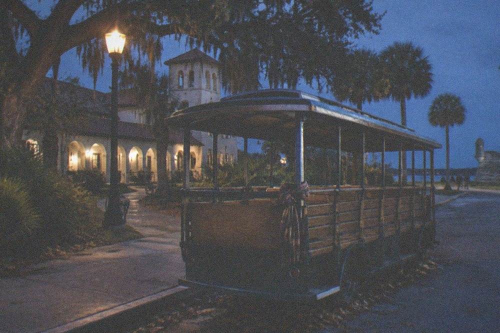 An open-air trolley parked on a lamplit street in the historic district