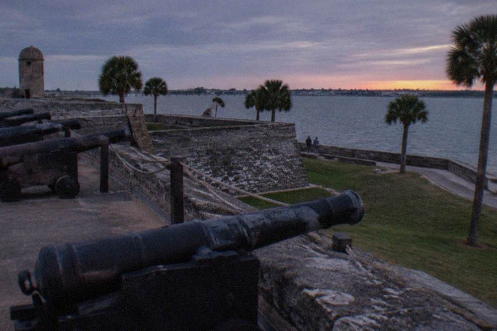 The dark coquina walls of the Castillo de San Marcos under an evening sky