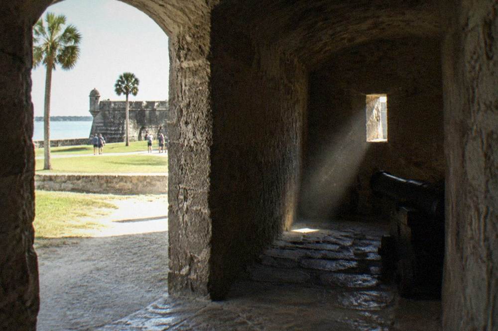 A dim stone passage inside the Castillo de San Marcos with an arched doorway