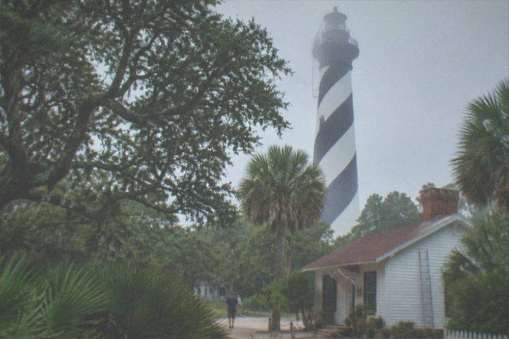The black and white striped St. Augustine Lighthouse above maritime tree cover