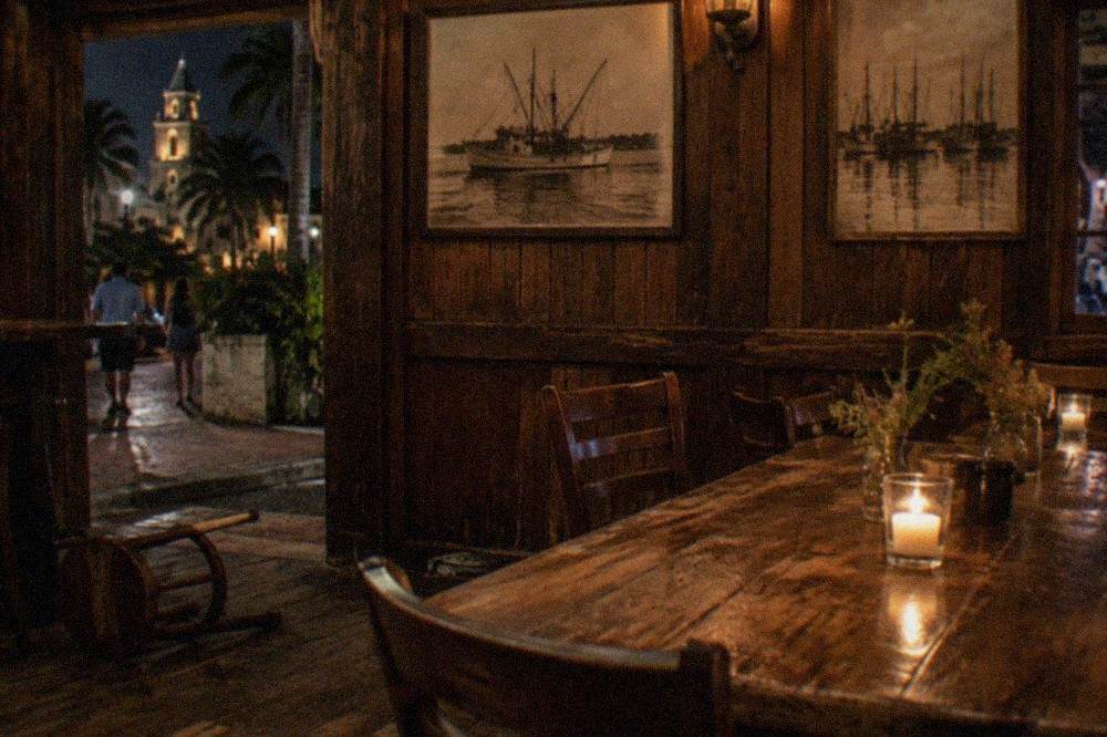 A candlelit bar interior in an old wooden building with historic photographs on the walls