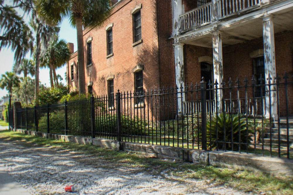 The brick exterior of the Old Jail behind iron fencing
