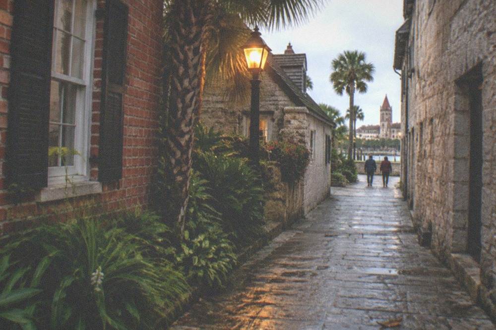 A dim narrow alley between old brick buildings lit by a single lamp