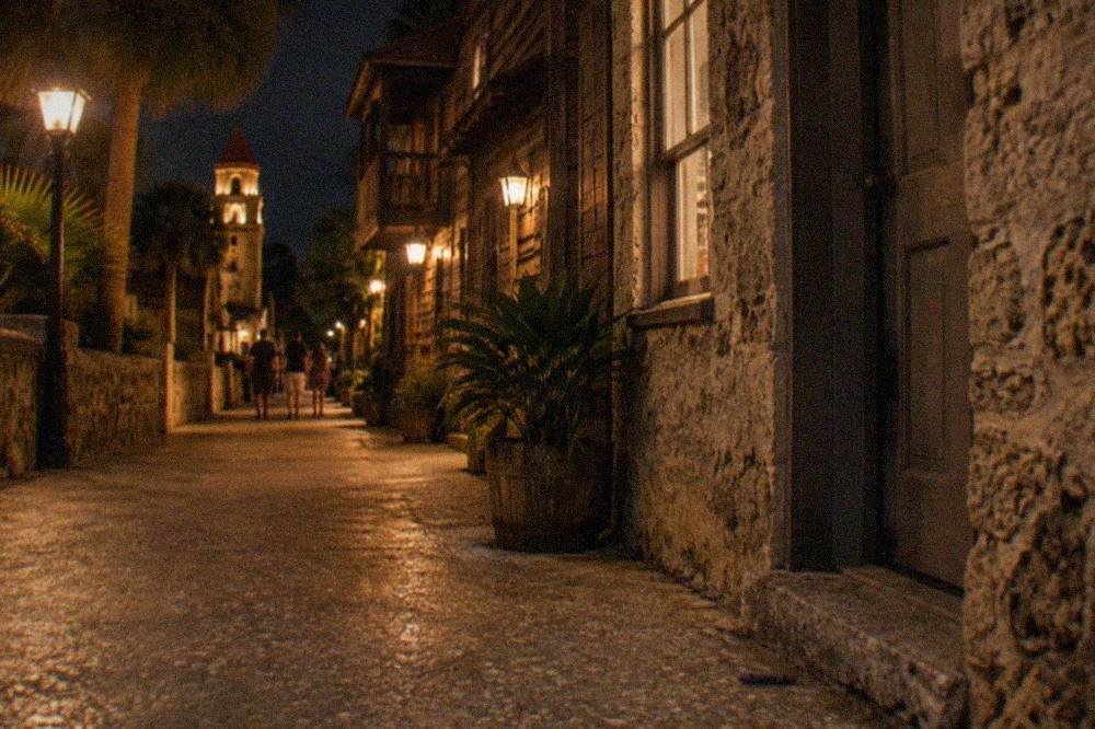 A narrow lamplit lane between old coquina buildings in St. Augustine