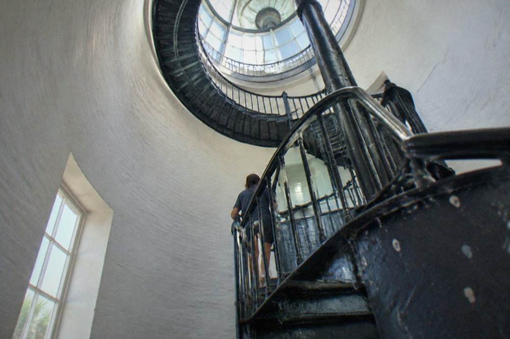 The spiral staircase inside the lighthouse curving upward toward the lamp room