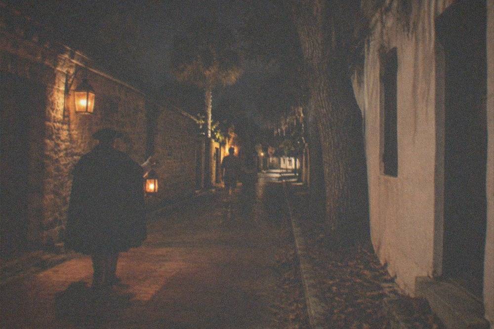 Lantern-lit colonial street with historic buildings at night