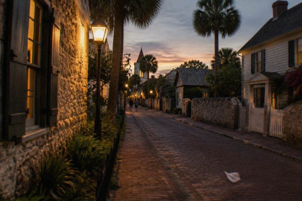 Night view of a lamplit colonial street with historic coquina walls