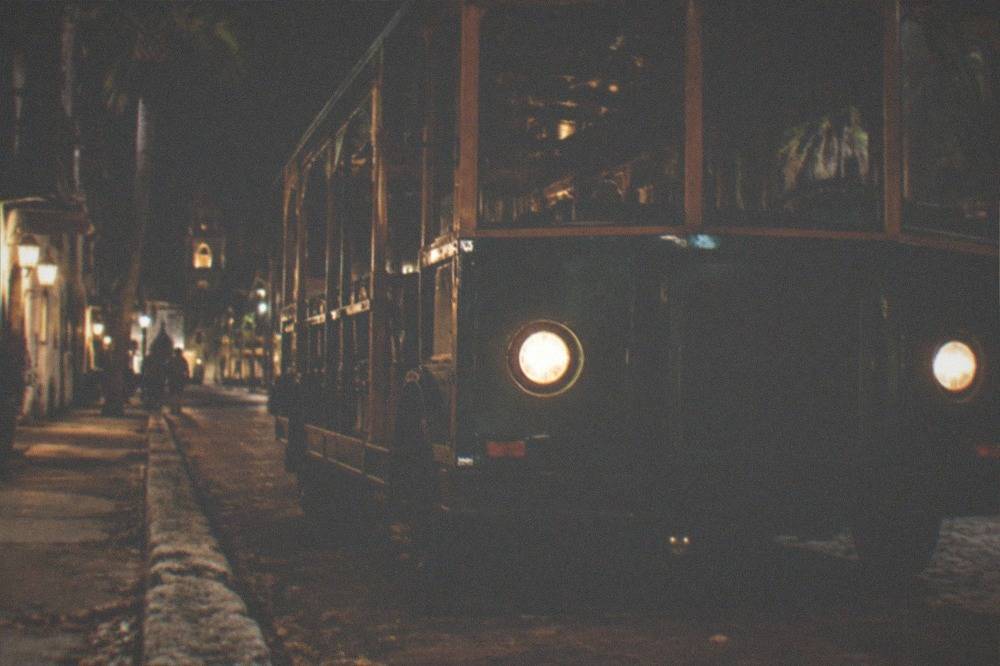 An open-air trolley parked on a downtown street after dark